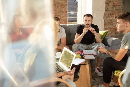 Group of young caucasian office workers meeting to discuss new ideas. Creative meeting. Teamwork and brainstorming. Men and women meet in office to plan their future working. Business concept.の写真素材