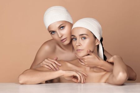 Portrait of beautiful young women isolated on brown studio background. Caucasian female models looking at camera and posing. Concept of womens health and beauty, self-care, body, skin care, treatment.の写真素材