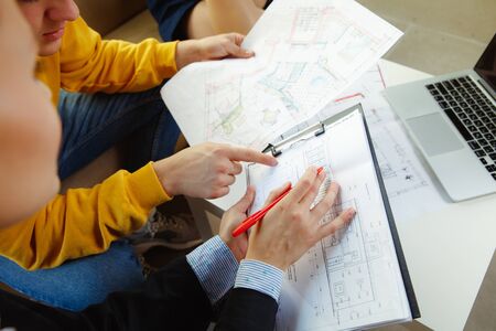 Interior designer working with young couple. Lovely family and professional designer or architector...