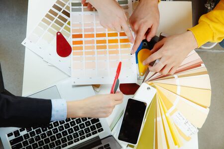 Interior designer working with young couple. Lovely family and professional designer or architector...