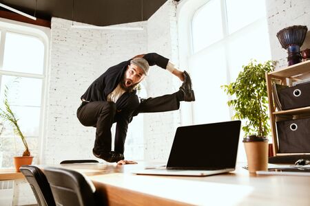 Young caucasian businessman having fun  break dance in the modern officeの写真素材