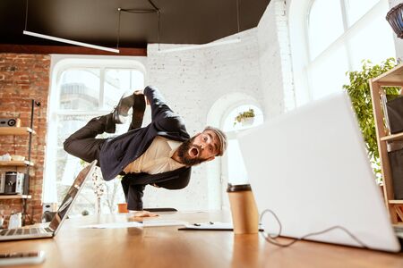 Young caucasian businessman having fun  break dance in the modern officeの写真素材