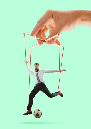 Man like a puppet in somebodies hands on green background. Concept of unfair manipulation, phycology of exploitation, mental technique, motivation. Puppets and their masters. Possessive relationship.の写真素材