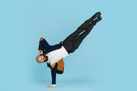 Young caucasian businessman having fun dancing break dance on blue studio background. Management, flexible, freedom, professional occupation, alternative way of modern working. Loves his job. Copyspace.の写真素材