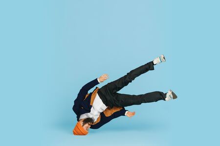 Young caucasian businessman having fun dancing break dance on blue studio background. Management,...