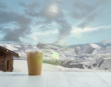 Single tea or coffee mug and landscape of mountains on background. Cup of hot drink with snowly look...