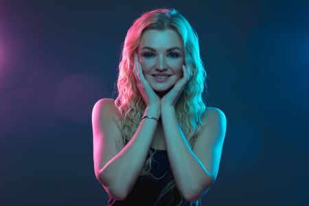Caucasian young womans portrait on gradient background in neon light. Beautiful female model with unusual look. Concept of human emotions, facial expression, sales, ad. Looks cute and smiling.の写真素材
