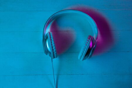 Top view of set of gadgets in purple neon light and blue background. Headphones on wooden table. Copyspace for your advertising. Tech, modern, gadgets.の写真素材