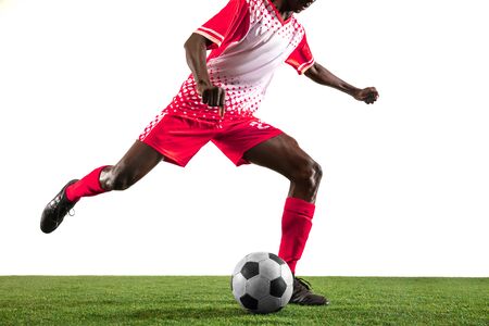Professional african-american football or soccer player of red team in motion isolated on white studio background. Fit man in action, excitement, emotional moment. Concept of movement at gameplay.の写真素材