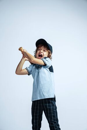 Pretty young curly boy in casual clothes on white studio background. Confident and cool with sport bat. Caucasian male preschooler with bright facial emotions. Childhood, expression, having fun.の写真素材