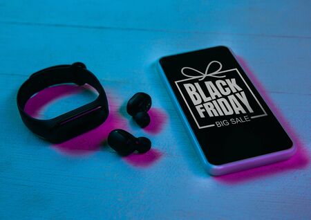 Top view of set of gadgets in purple neon light, blue background. Smartphone, smartwatches, headphones. Tech, modern, gadgets, ad. Black friday, cyber monday, sales, finance online purchases conceptの写真素材