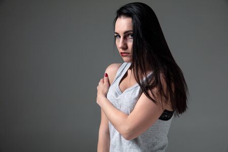 Woman in fear of domestic abuse and violence, concept of female rights. Caucasian brunette woman on grey background looks upset, sad, depressed being victim of man or husband. Has bruises, hematomas.の写真素材