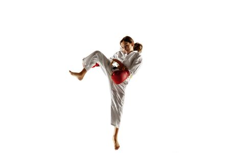 Confident junior in kimono practicing hand-to-hand combat, martial arts. Young female fighter with yellow belt s training on white studio background. Concept of healthy lifestyle, sport, action.の写真素材