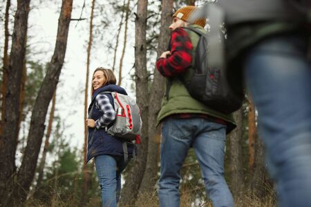 Group of friends on a camping or hiking trip in autumn day. Men and women with touristic backpacks...