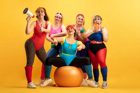 Young caucasian plus size female models training on yellow background. Copyspace. Concept of sport, healthy lifestyle, body positive, fashion. Friendship, girl power. Stylish woman posing, smiling.の写真素材