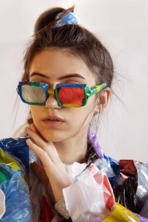 Woman wearing plastic on white background. Female model in clothes and shoes made of garbage. Fashion, style, recycling, eco and environmental concept. Too much pollution, were eating and taking it.の写真素材