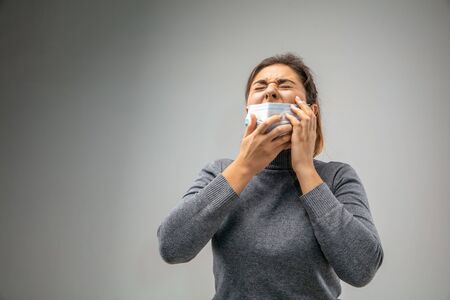 Cant breathe. Caucasian woman wearing the respiratory protection mask against air pollution and dust particles exceed the safety limits. Healthcare, environmental, ecology concept. Allergy, headache.の写真素材