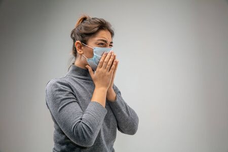 Cant breathe. Caucasian woman wearing the respiratory protection mask against air pollution and dust particles exceed the safety limits. Healthcare, environmental, ecology concept. Allergy, headache.の写真素材