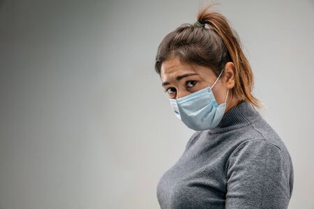 Awful living. Caucasian woman wearing the respiratory protection mask against air pollution and dust particles exceed the safety limits. Healthcare, environmental, ecology concept. Allergy, headache.の写真素材