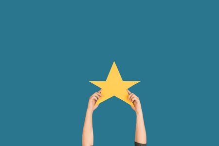 Hands holding the sign of star on blue studioの写真素材