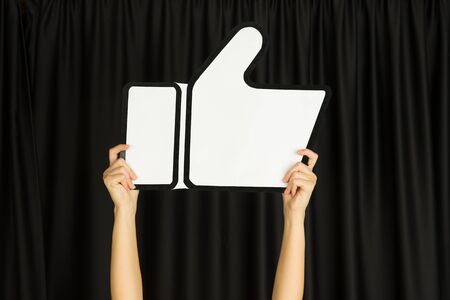 Hands holding the sign of like on black studioの写真素材