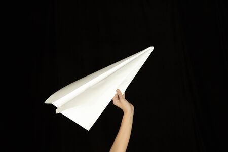 Hands holding the sign of paper airplane or message on black studio