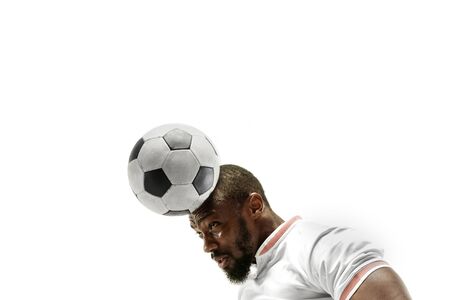 Close up of emotional african man playing soccer hitting the ball with the head on isolated white background. Football, sport, facial expression, human emotions, healthy lifestyle concept. Copyspace.の写真素材