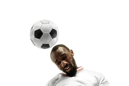Close up of emotional african man playing soccer hitting the ball with the head on isolated white background. Football, sport, facial expression, human emotions, healthy lifestyle concept. Copyspace.の写真素材