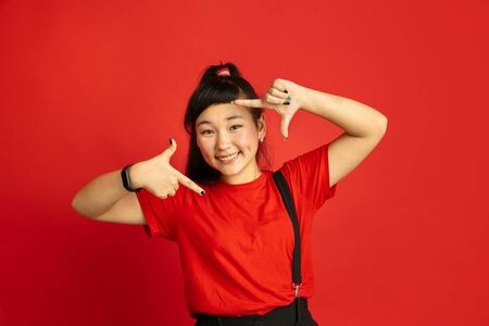 Asian teenagers portrait isolated on red studio background. Beautiful female brunette model with...