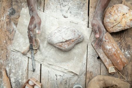 Top view of african-american man cooks fresh cereal, bread, bran on wooden table. Tasty eating,...