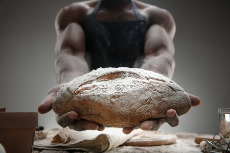 Close up of african-american man cooks fresh cereal, bread, bran on wooden table. Tasty eating,...