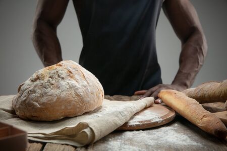 Close up of african-american man cooks fresh cereal, bread, bran on wooden table. Tasty eating,...