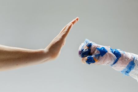 Big plastic hand made of garbage trying to fight another one on whiteの写真素材