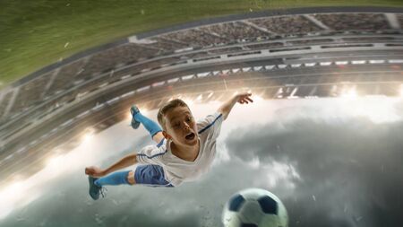Under the same sun. Young football or soccer player in sportwear and boots kicking ball for the goal...