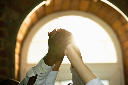 Close up of african-american and caucasian human's hands holding together. Female hands touching in...