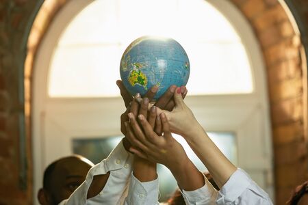 Close up of african-american and caucasian human's hands. Holding globe in sign of peace, national. Business, teamwork, studying, education, ad, finance, love and relationship, family concept.の写真素材