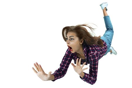 A second before falling. Caucasian young girl falling down in moment with bright emotions and facial expression. Female model in casual clothes. Shocked, scared, screaming. Copyspace for ad.の写真素材