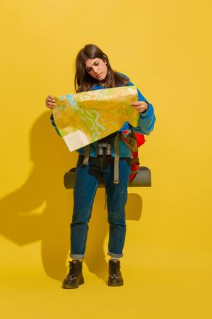 Smiling, looking for way. Portrait of a cheerful young caucasian tourist girl with bag and...