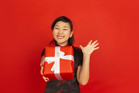 Giving giftbox. Happy Chinese New Year 2020. Asian young girls portrait isolated on red background....