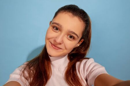 Posing for selfie taking. Caucasian teen girls portrait on blue