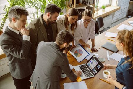 Teambuilding. Group of young business professionals having a meeting. Diverse group of coworkers discuss new decisions, plans, results, strategy. Creativity, workplace, business, finance, teamwork.の写真素材