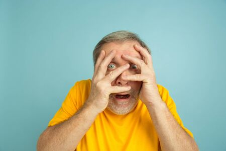 Shocked covering face with hands. Caucasian man portrait on blue studio background. Beautiful male...