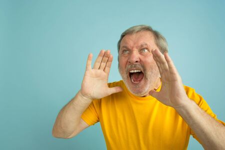 Calling, screaming. Caucasian man portrait isolated on blue studio background. Beautiful male model...