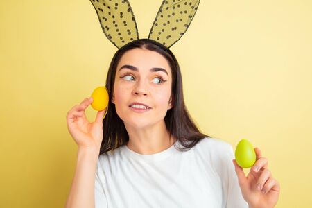 Egg hunt coming. Caucasian woman as an Easter bunny on yellow studio background. Happy easter...