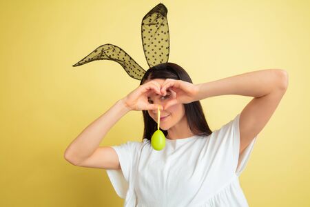Egg hunt coming. Caucasian woman as an Easter bunny on yellow studio background. Happy easter...