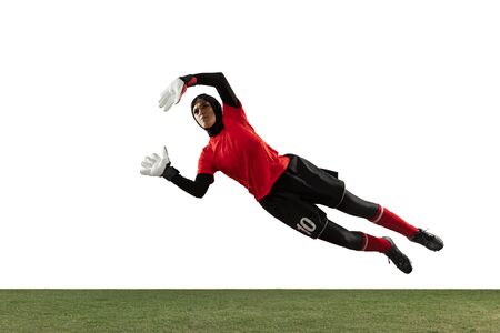 Arabian female soccer or football player, goalkeeper on white studio background. Young woman catching ball, training, protecting goals in motion and action. Concept of sport, hobby, healthy lifestyle.の写真素材