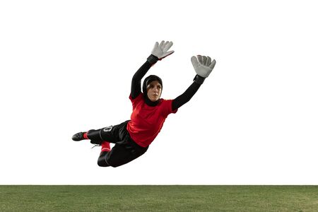 Arabian female soccer or football player, goalkeeper on white studio background. Young woman catching ball, training, protecting goals in motion and action. Concept of sport, hobby, healthy lifestyle.の写真素材
