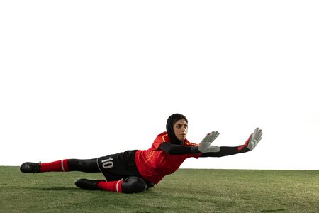 Arabian female soccer or football player, goalkeeper on white studio background. Young woman catching ball, training, protecting goals in motion and action. Concept of sport, hobby, healthy lifestyle.の写真素材