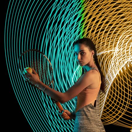 Creative sport on dark neon lighted line background. Tennis player training in action and motion on colorful waves. Concept of hobby, healthy lifestyle, youth, action, movement, modern style.の写真素材