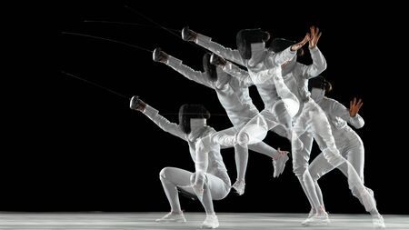 Teen girl in fencing costume with sword in hand on black background in strobe light. Young female...